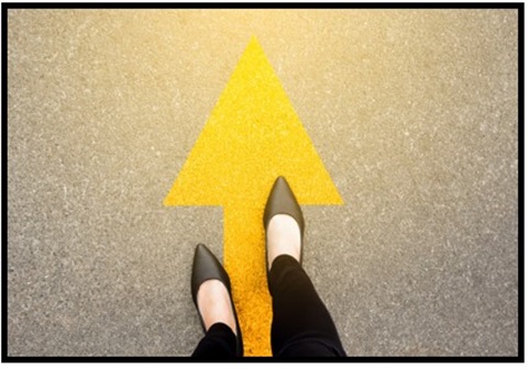 Overhead view of a person stepping on a yellow street painted arrow