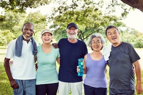 Five older adults standing together smiling