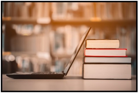 Open laptop next to a pile of books