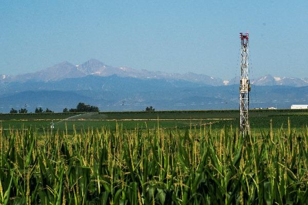An oil rig on farm ground with the mountains in the background